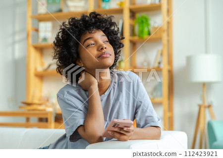 African girl holding smartphone touch screen typing scroll page at home. Woman with cell phone surfing internet using social media apps playing game. Shopping online Internet news cellphone addiction African girl holding smartphone touch screen typing scroll page at home. Woman with cell phone surfing internet using social media apps playing game. Shopping online Internet news cellphone addiction 112423921