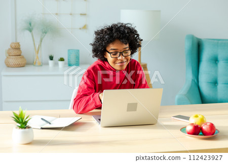 African american girl using laptop at home office looking at screen typing chatting reading writing email. Young woman having virtual meeting online chat video call conference. Work learning from home 112423927