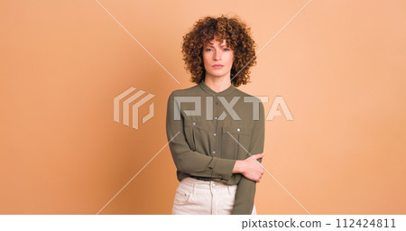 Standing charming young woman with curly hair in beige background 112424811