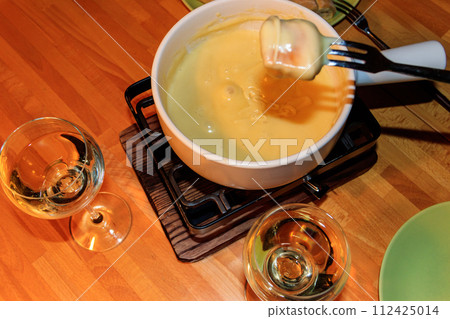Traditional cheese fondue and wine on wooden table. Swiss cuisine Traditional cheese fondue and wine on wooden table. Swiss cuisine 112425014