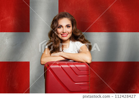 Love Denmark. Young woman with red suitcase on Danish flag background. Travel, work, education  112428427