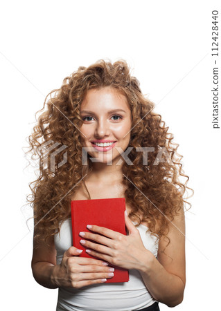 Beautiful happy young adult woman smiling and holding book with red empty cover Beautiful happy young adult woman smiling and holding book with red empty cover 112428440