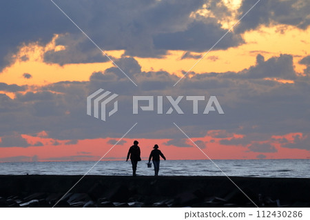 people walking on the beach at sunset people walking on the beach at sunset 112430286