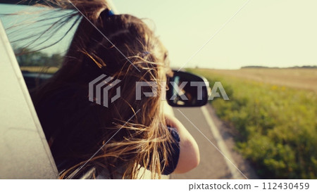 little girl dreams car window, following the road into the sunset. wind plays with hair, symbolizing freedom childhood. Family travel summer filled with joy holidays, child kid daughter childhood 112430459