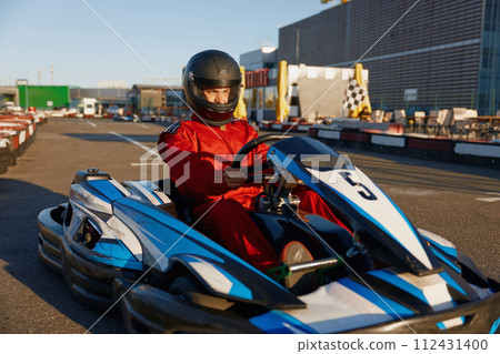 Go-cart racer moving fast on open air motor racing track 112431400