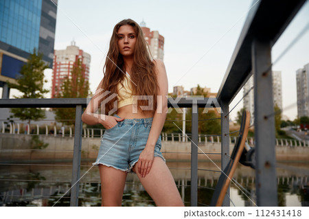 Cool hipster woman skateboarder posing for camera outdoors, youth culture Cool hipster woman skateboarder posing for camera outdoors, youth culture 112431418