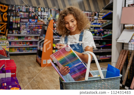 Happy girl child carrying shopping basket choosing studying supplies 112431483