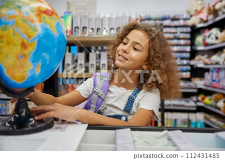Little girl playing with school earth globe while shopping education stationery 112431485
