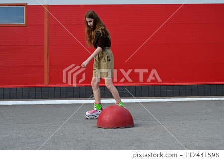 Full-length portrait of a smiling girl with long hair on roller skates 112431598