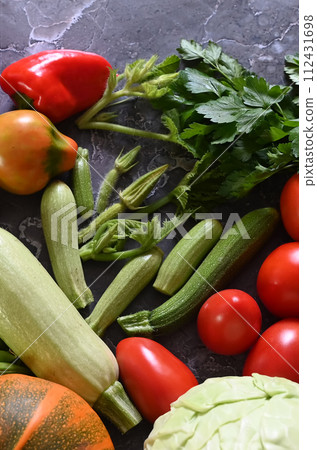 Food cooking background. Fresh rosemary, cilantro, basil, cherry tomatoes, peppers and olive oil, spices herbs and vegetables at black slate table. Food ingredients top view. 112431698