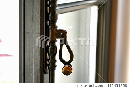 Close-up of a vintage metal window lever. Brass handle on the old wooden window 112431868