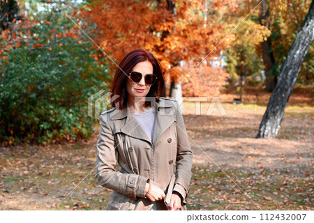a confident young slender woman in a raincoat and high-heeled shoes is talking on the phone in an autumn city, a woman is smiling and enjoying life a confident young slender woman in a raincoat and high-heeled shoes is talking on the phone in an autumn city, a woman is smiling and enjoying life 112432007