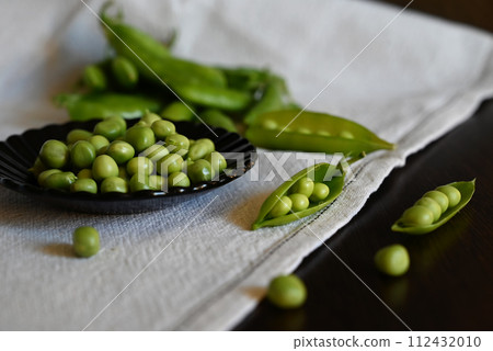 Green shoots of young peas, flowers and pods on a dark wooden background. selective focusing Green shoots of young peas, flowers and pods on a dark wooden background. selective focusing 112432010