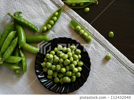Green shoots of young peas, flowers and pods on a dark wooden background. selective focusing 112432040