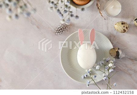 Easter composition of eggs and flowers on a light background. Easter bunny. A gentle greeting card for the Easter holiday.Top view, copy location, flat layout. 112432158
