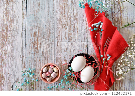 Create an Easter composition of Easter quail eggs and flowers on a wooden background. A gentle greeting card for the Easter holiday.Top view, copy location, flat layout. 112432171