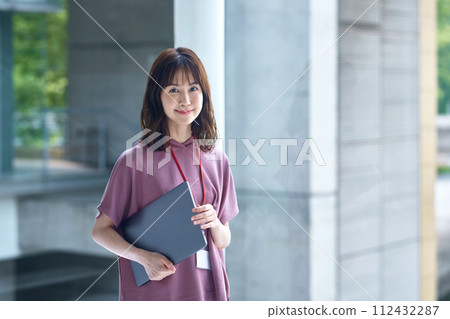 Young female engineer in casual outfit walking in office corridor Young female engineer in casual outfit walking in office corridor 112432287