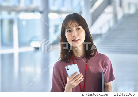 便衣的年輕女商人操作一個智能手機的在辦公室 112432309