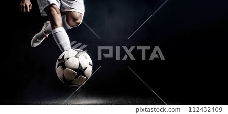 foot of football player hits ball in game, background is football stadium stadium. 112432409