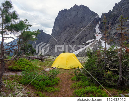 Dramatic landscape with yellow tent on forest hill among rocks 112432932