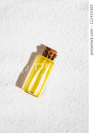Essential oil in glass bottle on sand, top view 112433305