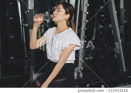 Woman drinking water at training gym 112433526
