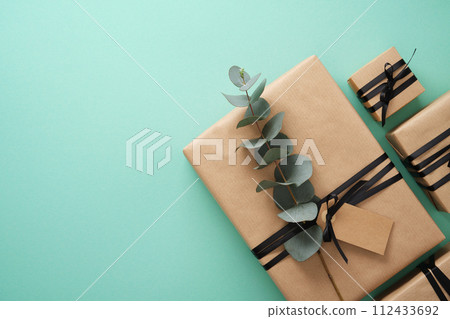 Brown craft gift boxes with black ribbons and Eucalyptus on mint background. Space for your text. 112433692