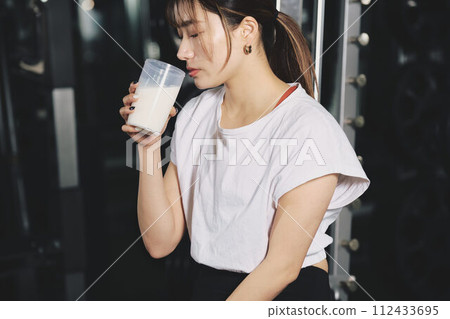 Woman drinking protein at training gym 112433695