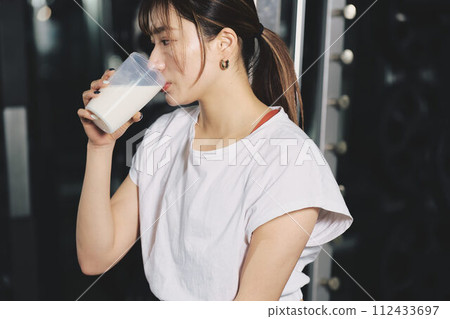 女人在健身房訓練時喝蛋白質 112433697