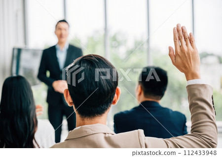 A conference audience with raised hands for questions, illustrating an interactive meeting. Group participation, diversity, and audience engagement at a workshop or seminar presentation. 112433948