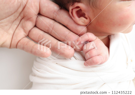 Close-up of baby's small hand, head, ear and palm of mother. Macro Photo of Newborn baby after birth tightly holding parents finger on white background. Family and home concept. Healthcare paediatrics Close-up of baby's small hand, head, ear and palm of mother. Macro Photo of Newborn baby after birth tightly holding parents finger on white background. Family and home concept. Healthcare paediatrics 112435222