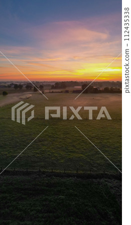 Pastoral Dawn: Serene Sunrise Over a Tranquil Countryside 112435338