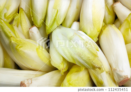 Stack of Belgian endives on a market stall Stack of Belgian endives on a market stall 112435451
