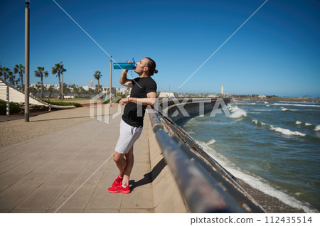 Young athletic man, sportsman, resting, drinking water after a workout outdoor. Young athletic man, sportsman, resting, drinking water after a workout outdoor. 112435514
