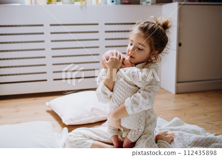 Portrait of big sister holding newborn sister. Girl carefully cuddling small baby. Sisterly love, joy for new family member. 112435898