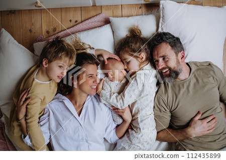 Top view of family lying in bed with kids and newborn baby. Perfect moment. Strong family, bonding and parents' unconditional love for their children. 112435899