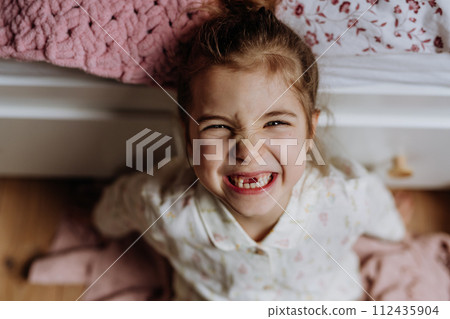 Portrait of cute girl smiling with gap-toothed grin, missing her baby teeth. 112435904