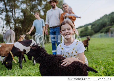 Portrait of farmer family petting donkey and goats on their farm. A gray mule and goats as a farm animals at the family farm. 112436254