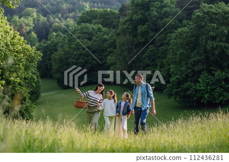 Family on walk in forest, going through meadow. Picking mushrooms, herbs, flowers picking in basket, foraging. Concept of family ecological hobby in nature. Family on walk in forest, going through meadow. Picking mushrooms, herbs, flowers picking in basket, foraging. Concept of family ecological hobby in nature. 112436281