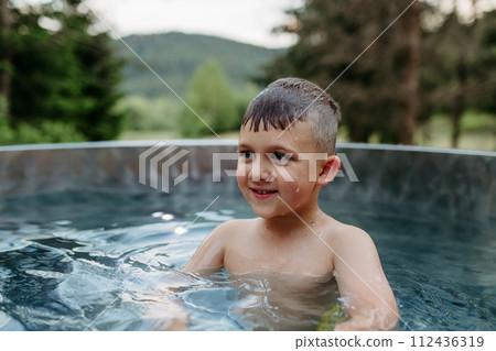 Little boy enjoying summer time in outdoor pool with his family, having fun. 112436319