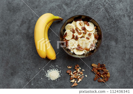 Healthy breakfast concept with oatmeal porridge with bananas,  nuts, raisins, sesame seeds  Top view. Super food. Food made of granola and musli. 112436341