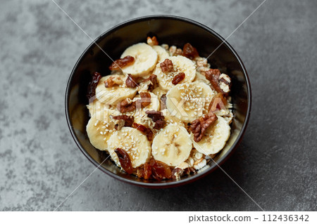Healthy breakfast concept with oatmeal porridge with bananas,  nuts, raisins, sesame seeds  Top view. Super food. Food made of granola and musli. 112436342