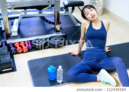 A young woman training her body at a personal gym, taking a break, feeling tired, unable to continue, muscle training girl, clearly 112436384