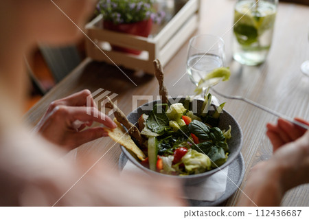 Close up of vegetable salad serving in restaurant, customer eating healthy food from bowl. 112436687