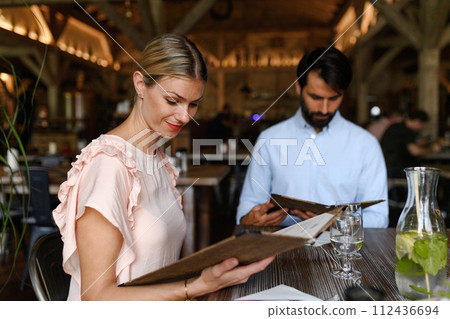 Husband and wife choosing food from menu. Happy loving couple at date in restaurant. 112436694