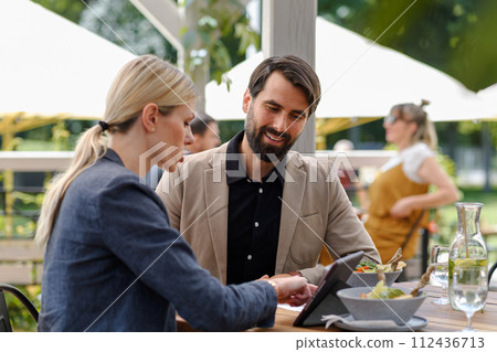 Business lunch for two managers, discussing new business project. Couple sitting outdoors on terrace restaurant, having dinner date. 112436713