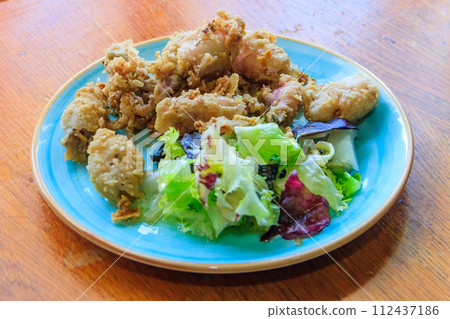 Crispy deep fried baby octopus served with salad on wooden table 112437186