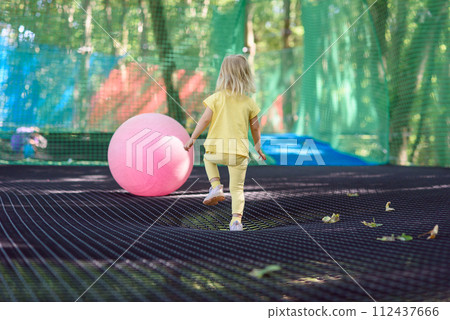 Little girl having fun at a rope playground. The girl is playing on net ropes. 112437666