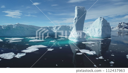 Towering melting iceberg global warming concept. Snow covered glacier float turquoise ocean water in sunny summer day. Polar climate change issue. Wild Antarctica nature environment. Close up panorama Towering melting iceberg global warming concept. Snow covered glacier float turquoise ocean water in sunny summer day. Polar climate change issue. Wild Antarctica nature environment. Close up panorama 112437963
