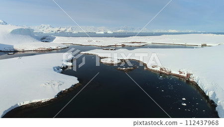 Fly above frozen panorama of Antarctic and old polar science wooden building. Antarctica majestic landscape drone view. Breathtaking harmony of untouched nature. Polar frozen ocean landscape Fly above frozen panorama of Antarctic and old polar science wooden building. Antarctica majestic landscape drone view. Breathtaking harmony of untouched nature. Polar frozen ocean landscape 112437968